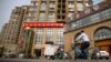 FILE - A delivery cart and cyclist ride past a building housing the Fengrui law firm in Beijing. Several lawyers from the firm have been targeted by authorities.