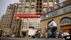 FILE - A delivery cart and cyclist ride past a building housing the Fengrui law firm in Beijing. Several lawyers from the firm have been targeted by authorities.