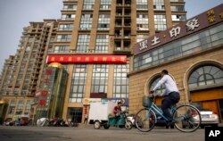 FILE - A delivery cart and cyclist ride past a building housing the Fengrui law firm in Beijing.