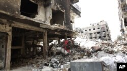 FILE - Rubble and heavy damage remain on a deserted street during a government escorted visit to Yarmouk refugee camp in Damascus, Syria, April 9, 2015. The United Nations brokered a deal to relocate some IS fighters and their families.