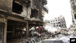 FILE - Rubble and heavy damage remain on a deserted street during a government escorted visit to Yarmouk refugee camp in Damascus, Syria, April 9, 2015. The United Nations brokered a deal to relocate some IS fighters and their families.