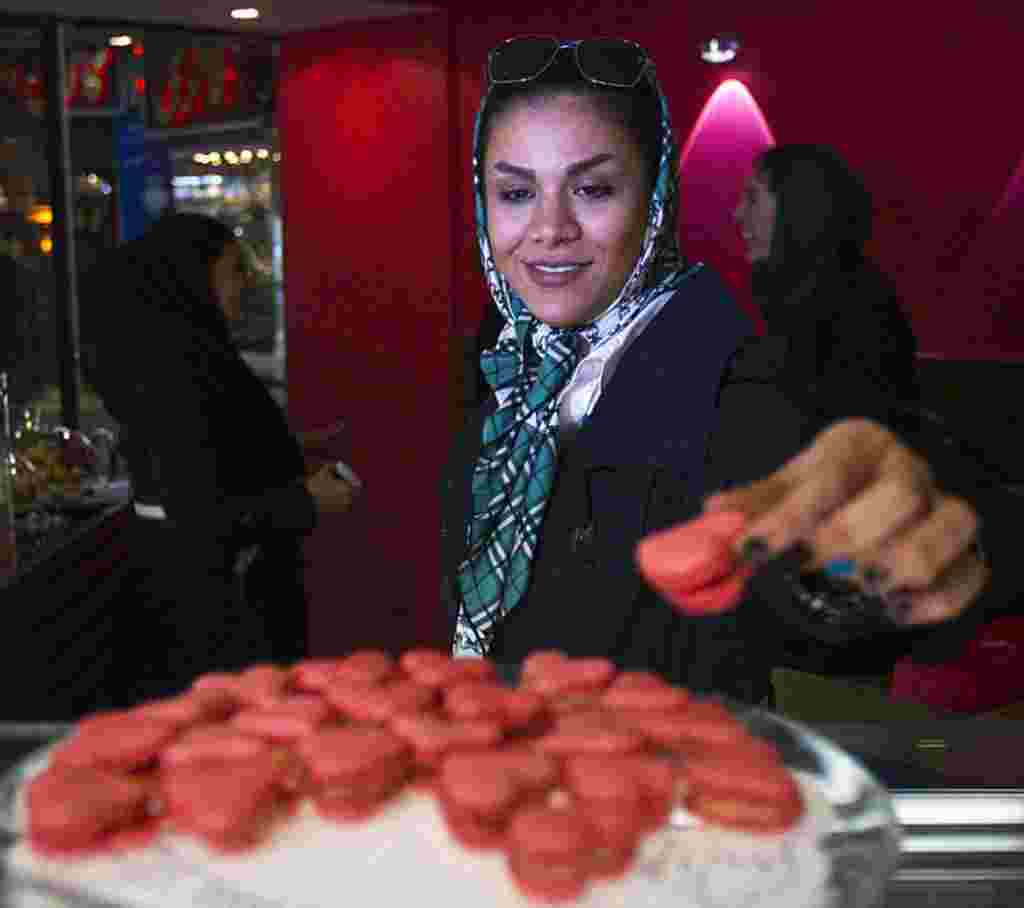 Seorang perempuan di Iran mengambil sebuah kue berbentuk hati berwarna merah muda di sebuah bakery di Teheran, 13 Februari (Reuters).