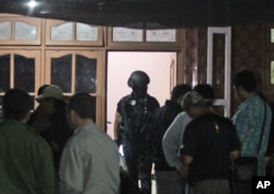 FILE - Indonesian police officers of Special Detachment 88 anti-terror unit search for evidence following a raid on a house used as a hideout by suspected militants' in Mojokerto, East Java, Indonesia, Dec. 19, 2015.