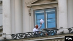 Iranian Foreign Minister Mohamad Javad Zarif waves a document over his head, saying "we still have work," on a balcony of the Palais Coburg where closed-door nuclear talks take place in Vienna, Austria, July 12, 2015. (Brian Allen/VOA)