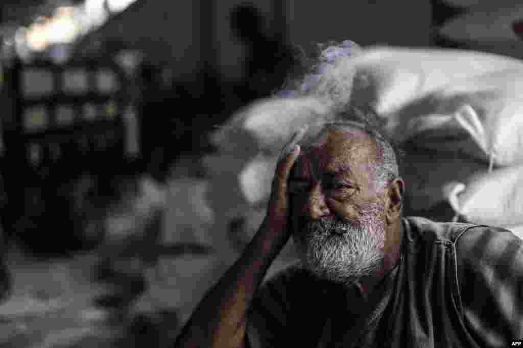 A Palestinian man smokes as he waits to receive aid at a United Nations food distribution centre in Jabalia refugee camp in the northern Gaza Strip.