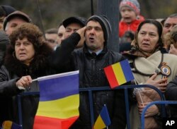 Romanians sing the national anthem during the national day military parade in Bucharest, Dec. 1, 2017.