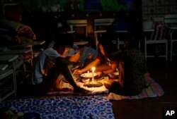 A family shares a meal using a flashlight inside a temporary evacuation center as electricity was shut off following the onslaught of Typhoon Mangkhut in Tuguegarao city in Cagayan province, northeastern Philippines, Sept. 15, 2018.