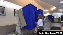 FILE - A woman enters a curtained voting machine at a polling station, in Philadelphia, Pa., April 26, 2016. 