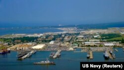 FILE - Guided missile destroyer USS Ross pulls into Naval Station Norfolk, Virginia, July 7, 2011. Eleven current or former U.S. Navy officials have been charged in a bribery investigation.