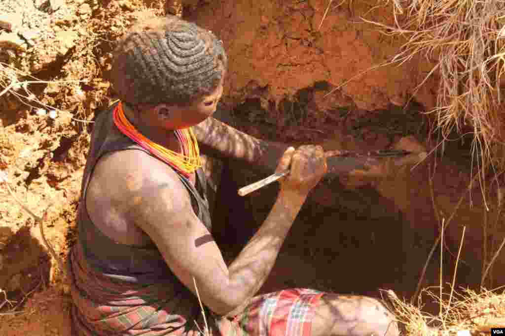 Uma mineira usa uma ferramenta para limpar a terra, que depois vai misturar com água para peneirar o ouro. Março 2, 2014. (Hilary Heuler for VOA)