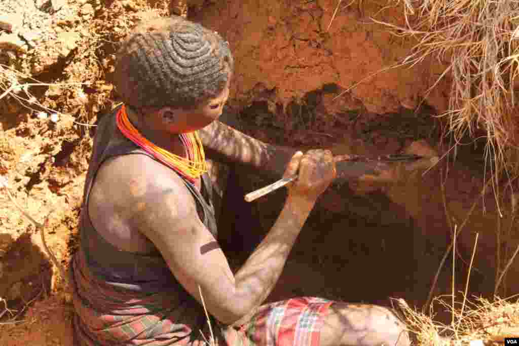 Mchimbaji anatumia chuma kuchimba mchanga, ambao atakusanya na kuchanganya na maji na kung&#39;uta ili kupata dhahabu, March 2, 2014. (Hilary Heuler for VOA)