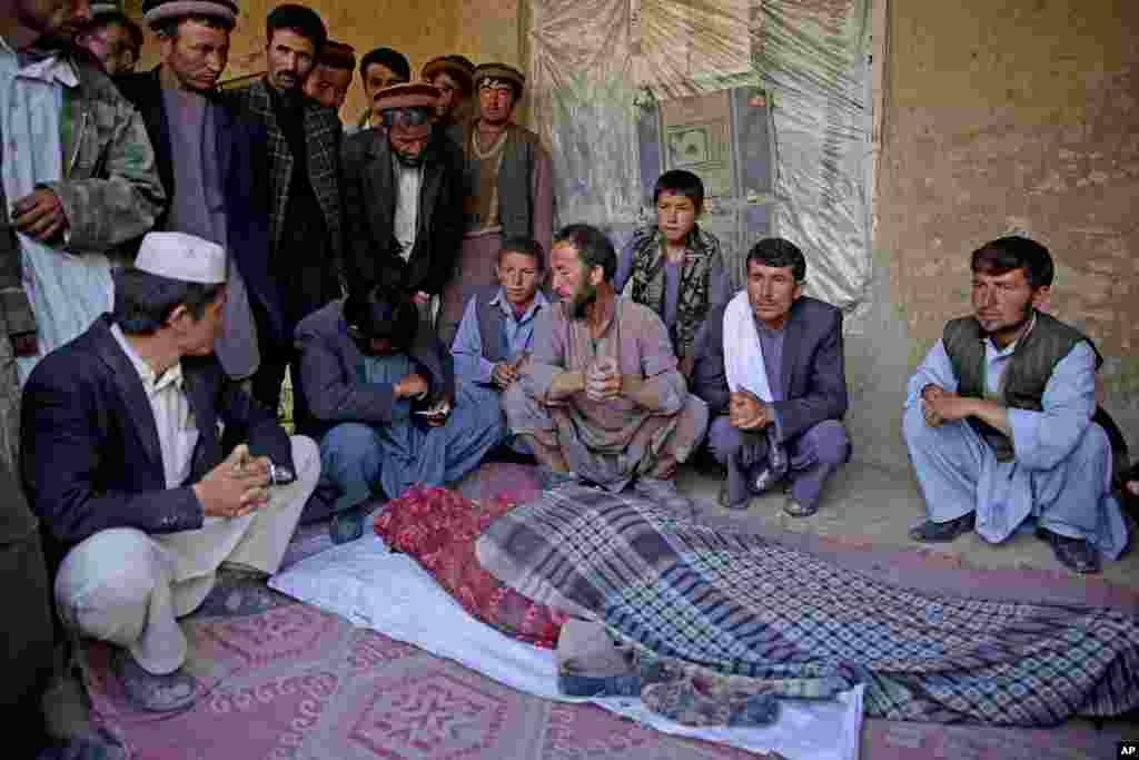 Survivors gather around the lifeless body of a woman after her body was recovered from the landslide that buried Abi-Barik village, Badakhshan province, northeastern Afghanistan, May 6, 2014.