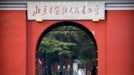 In this Jan. 27, 2020, photo, members of a group of foreign tourists wearing face masks to protect against the coronavirus walk through a public park near the Forbidden City in Beijing. The U.S. has issued a new travel advisory.