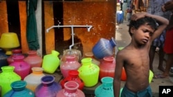 In this Thursday, July 18, 2019, photo, a boy waits at a water distribution point in Chennai, capital of the southern Indian state of Tamil Nadu. (AP Photo/Manish Swarup)