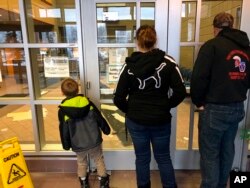 People stand outside the police headquarters building in Anchorage, Alaska, after it was closed following an earthquake, Nov. 30, 2018.