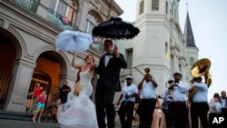 In this August 15, 2015, file photo, newlyweds dance their way out of St. Louis Cathedral at Jackson Square in the French Quarter of New Orleans. Catholic faith and traditions have played a role in New Orleans' culture since Feb. 9, 1718, when a priest plan