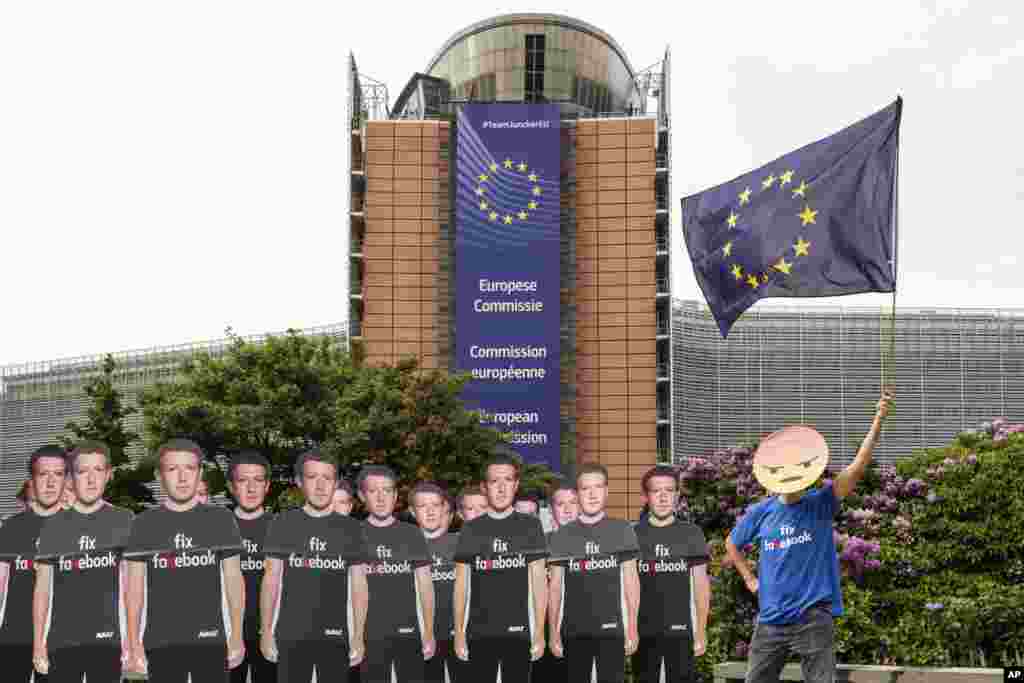 An Avaaz demonstrator waves the European flag as he stands next to life-sized Zuckerberg cutouts to protest against fake Facebook accounts spreading disinformation on the platform, near the EU Commission in Brussels, Belgium.
