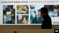 红十字会工作人员走过显示朝韩离散家庭团聚的图片（2014年3月6日）