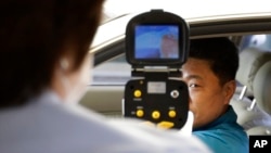 FILE - A South Korean official, left, uses a thermal camera to checks the body temperature of a driver as a precaution against Middle East Respiratory Syndrome (MERS) after he returned from Kaesong, North Korea, near Panmunjom, South Korea, June 13, 2015.