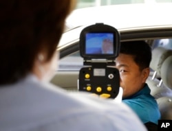 FILE - A South Korean official, left, uses a thermal camera to checks the body temperature of a driver as a precaution against Middle East Respiratory Syndrome (MERS) after he returned from Kaesong, North Korea, near Panmunjom, South Korea, June 13, 2015.