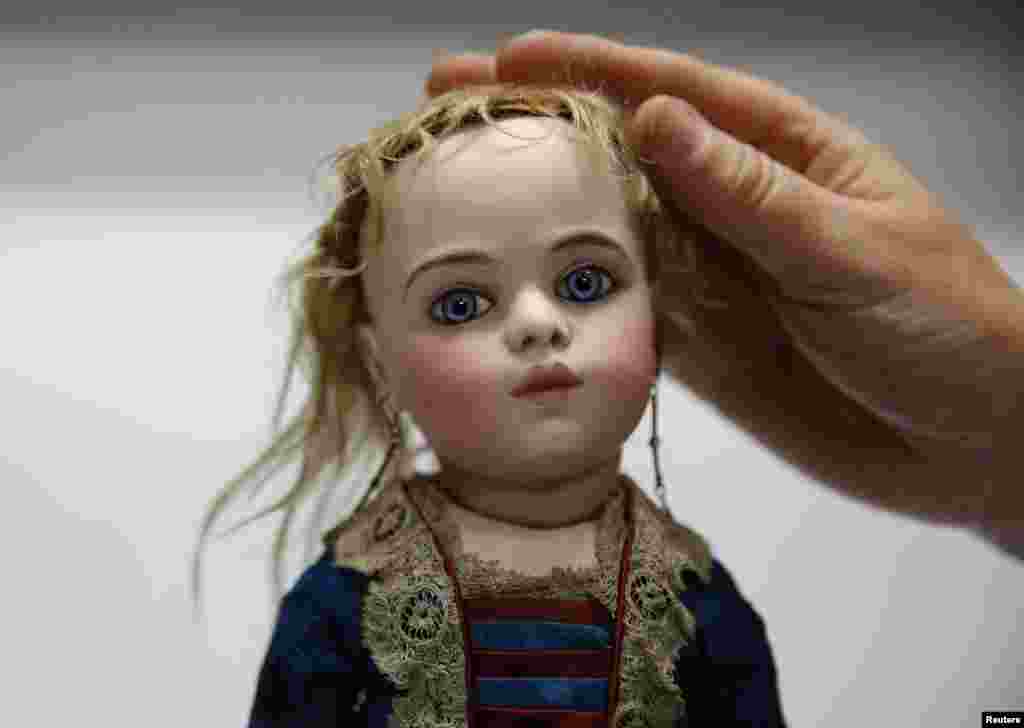 영국 벡티스 경매소 직원이 1880년 경 만들어진 프랑스 옹기 인형의 머리카락을 정리하고 있다. 이 인형은 미화 9천 달러에서 1만2천 달러 정도의 가격에 팔릴 것으로 예상된다.