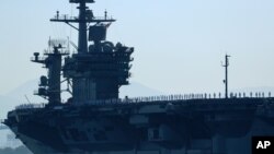 FILE - The aircraft carrier USS Theodore Roosevelt, with sailors manning the rails, leaves port on deployment, Oct. 6, 2017.
