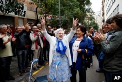 In this Oct. 1, 2017 photo, an elderly lady is applauded as she celebrates after voting at a school assigned to be a polling station in Barcelona, Spain.