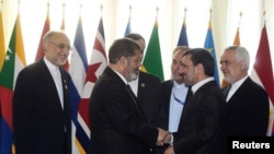 Eron prezidenti Mahmud Ahmadinejod (o'ngda) Misr prezidenti Muhammad Mursiy bilan qo'l berib ko'rishmoqda, Tehron, 30-avgust, 2012-yil.