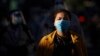 FILE - A woman wearing a face mask waits with dozens of others to get a coronavirus test at the National Stadium in Phnom Penh, Cambodia, Tuesday, Dec. 8, 2020.