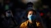 FILE - A girl wearing a face mask waits with dozens of others to get a coronavirus test at the National Stadium in Phnom Penh, Cambodia, Tuesday, Dec. 8, 2020.