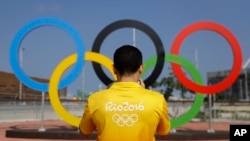 FILE - A volunteer photographs a set of Olympic Rings at Olympic Park in Rio de Janeiro, Brazil, July 29, 2016.