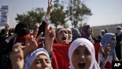 Syrians, who fled their homes due to fighting between the Syrian army and the rebels, shout slogans as they march toward the Turkish side of the border, August 28, 2012 