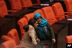 FILE - Huda Kaya (R), a legislator with pro-Kurdish Peoples' Democratic Party, (HDP), embraces Selina Dogan (L), of main opposition Republican People's Party (CHP), in the parliament in Ankara prior to deliberations over a controversial package of constit