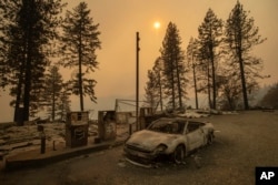 As the Camp Fire burns nearby, a scorched car rests by gas pumps near Pulga, Calif., Nov. 11, 2018.