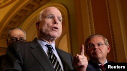 FILE - U.S. Senator John McCain, flanked by fellow senator, Robert Menendez (R), speaks to the media after the Senate passed the immigration reform bill, on Capitol Hill, June 27, 2013.