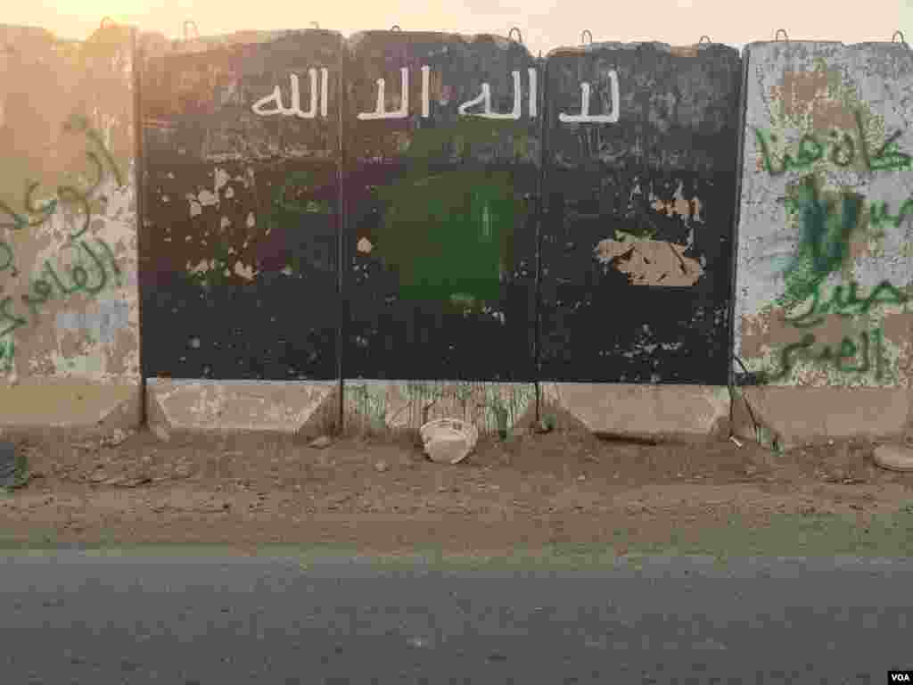 Di sebuah pangkalan angkatan darat Irak dekat Mosul, papan tanda kelompok militan Negara Islam (ISIS) ditimpa cat dan grafiti, di Qayyarah, Irak (24/10). (VOA/H. Murdock)