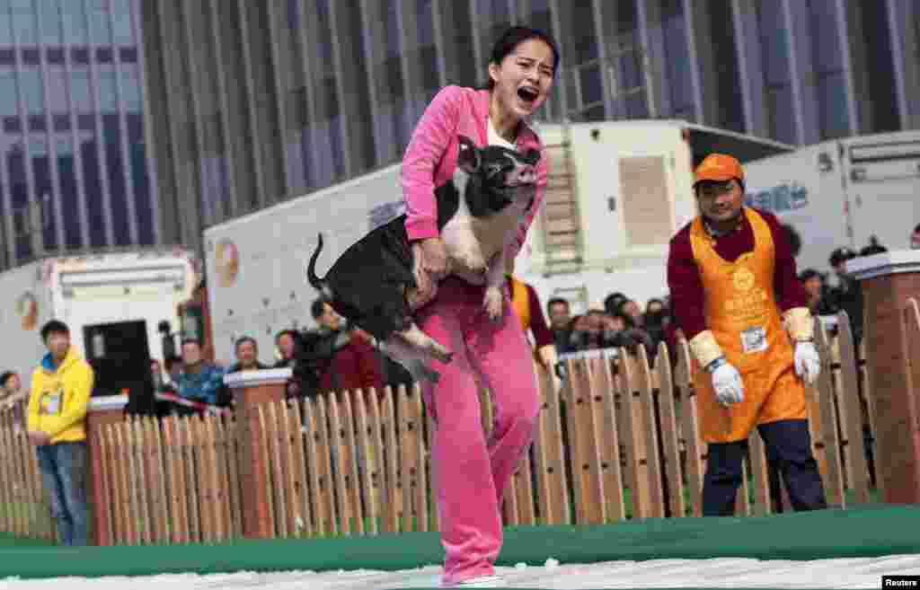 A woman carries a piglet as she runs on ice during a running challenge in Changsha, Hunan province, China. A total of 20 people participated in the challenge requiring them to choose a pig ranging between 15 kg and 115 kg in weight, and carrying it while running on a 20.15-meter-long ice track.