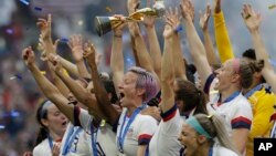 Pesepak bola putri AS, Megan Rapinoe, mengacungkan trofi setelah memenangkan laga final Piala Dunia Putri FIFA antara AS dan Belanda di Stade de Lyon, di Decines, di luar Kota Lyon, Perancis, 7 Juli 2019. (Foto: AP)