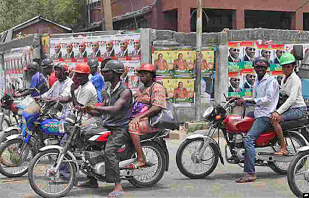 Motorcyclists wait at a traffic stop in front of election campaign posters in Yaba, Lagos, Nigeria, March 30, 2011