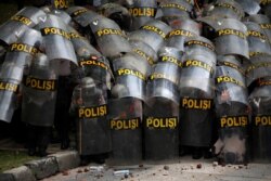 Para petugas polisi tampak melindungi diri mereka dengan tameng ketika melakukan pengamanan dalam aksi unjuk rasa penentangan terhadap Undang-undang Omnibus di Jakarta, pada 13 Oktober 2020. (Foto: Reuters/Willy Kurniawan)