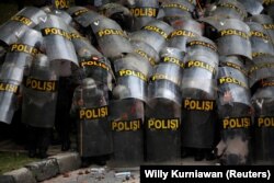 Para petugas polisi tampak melindungi diri mereka dengan tameng ketika melakukan pengamanan dalam aksi unjuk rasa penentangan terhadap Undang-undang Omnibus di Jakarta, pada 13 Oktober 2020. (Foto: Reuters/Willy Kurniawan)