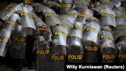 Para petugas polisi tampak melindungi diri mereka dengan tameng ketika melakukan pengamanan dalam aksi unjuk rasa penentangan terhadap Undang-undang Omnibus di Jakarta, pada 13 Oktober 2020. (Foto: Reuters/Willy Kurniawan)