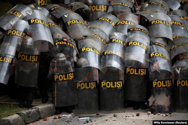 Para petugas polisi tampak melindungi diri mereka dengan tameng ketika melakukan pengamanan dalam aksi unjuk rasa penentangan terhadap Undang-undang Omnibus di Jakarta, pada 13 Oktober 2020. (Foto: Reuters/Willy Kurniawan)