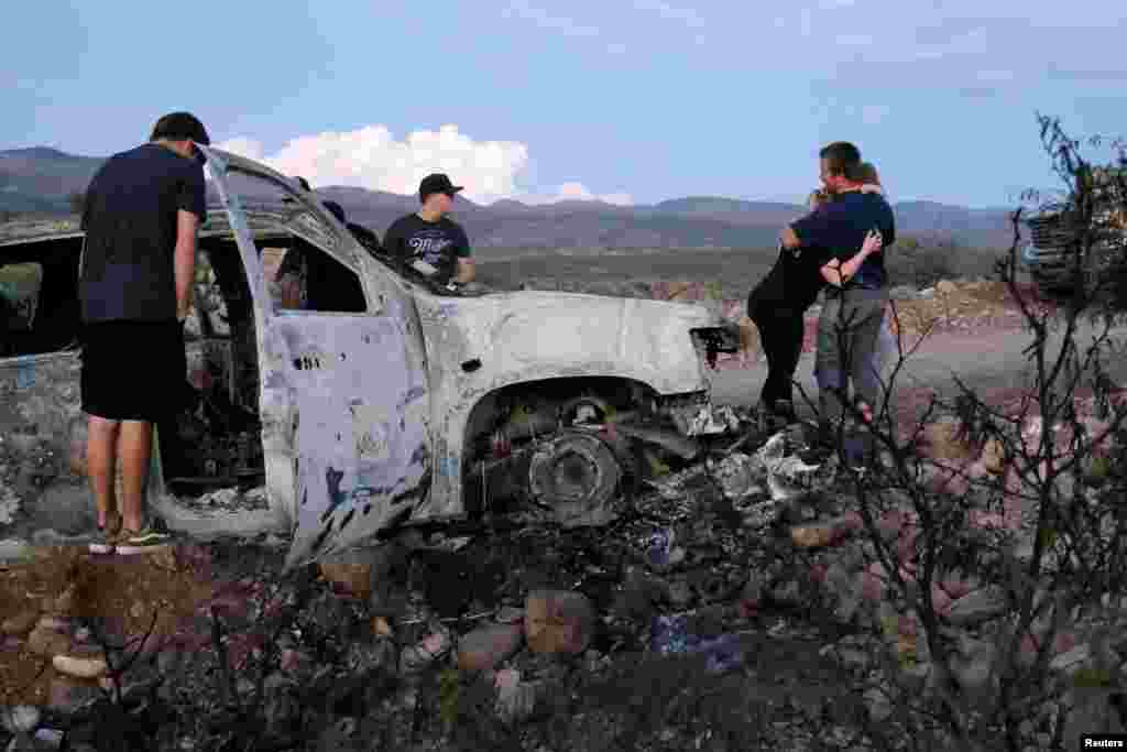 Relatives of slain members of Mexican-American families belonging to Mormon communities observe the burnt wreckage of a vehicle where some of their relatives were killed, in Bavispe, Sonora state, Mexico, Nov. 5, 2019.