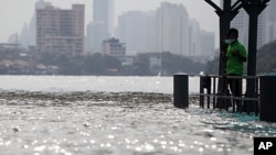 A man stands on a flooded pier at Memorial bridge, along the Chao Praya river, in Bangkok, October 14, 2011.