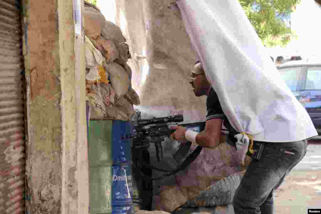 A Sunni Muslim gunman takes position behind sandbags at the Sunni Muslim dominant Bab al-Tebbaneh neighbourhood in Tripoli, northern Lebanon, during clashes with Alawites, August 21, 2012 .
