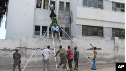 Survivors escape from window of besieged court complex in Mogadishu, Somalia, April 14, 2013.