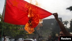 Hành động lấn lướt của Trung Quốc ở biển Đông đã làm bùng ra nhiều cuộc biểu tình bài Bắc Kinh tại các quốc gia cũng có tuyên bố chủ quyền ở biển Đông. Trong ảnh là một người biểu tình Philippines đốt cờ của Trung Quốc.