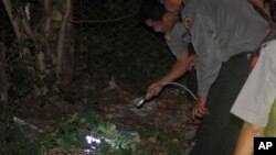  Burma police officers use a torch light as they examine the scene of a small explosion in which two young men were injured, on the outskirts of Rangoon, Burma, Oct. 13, 2013.