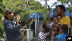 In this March 9, 2018 photo, Venezuelan Kritce Montero and her husband Hector Espinosa stand with their children, 6-month-old Hector, their 7-year-old daughter, right, and an unidentified family member, after getting their documents to enter Brazil.